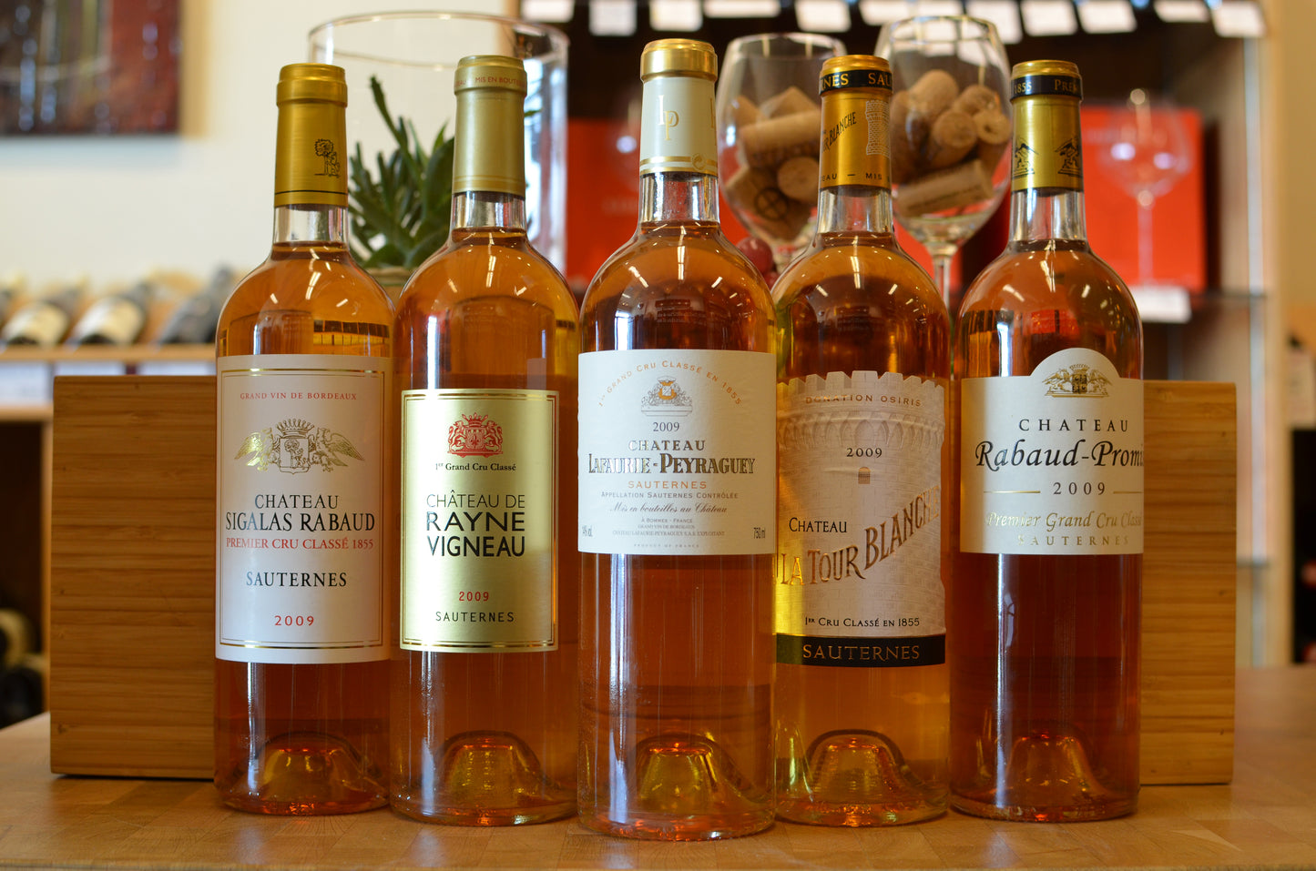 5 bottles of Sauternes wine in a row in front of a wooden box