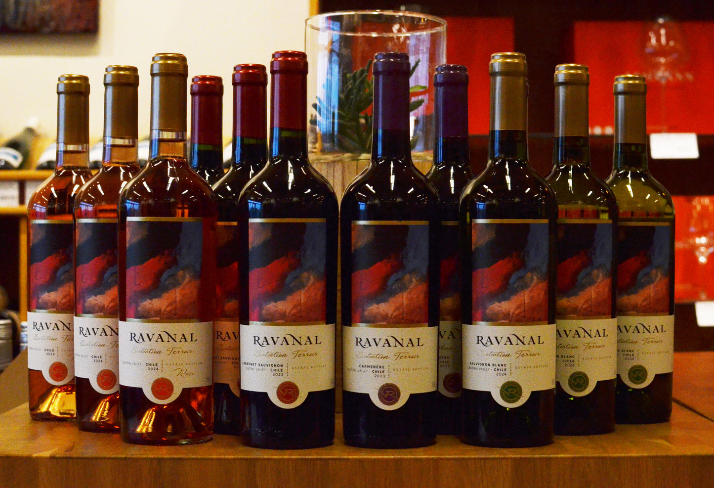 Row of mixed Ravanal wine bottles on a wooden surface with a blurred background
