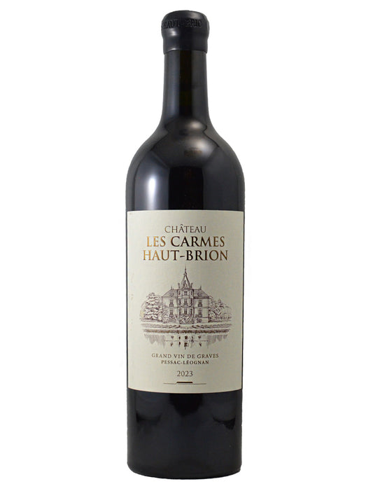 A bottle of Château Les Carmes Haut-Brion 2023 red wine, featuring a dark glass bottle with a cream-colored label and gold lettering plus an etched-style drawing of a chateau, set against a plain white background.