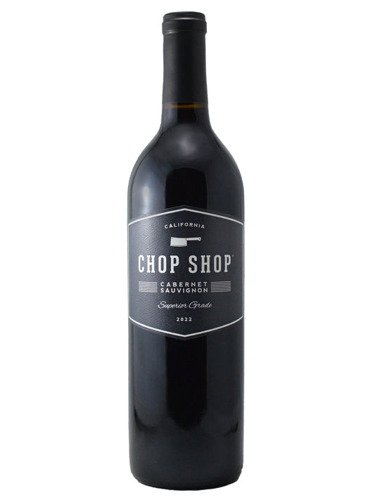 A bottle of Chop Shop Cabernet Sauvignon 2022 red wine with a dark label and a meat cleaver icon and 'California' above the name, bottle against white background
