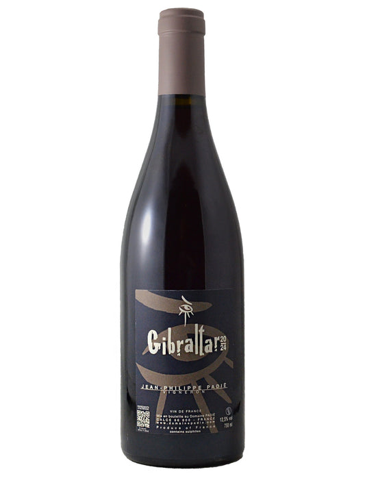 Dark coloured bottle of wine with a tan/grey enclosure and a black label with tan/grey/white 'eye' simply "painted" artwork and text. All set against a white background.