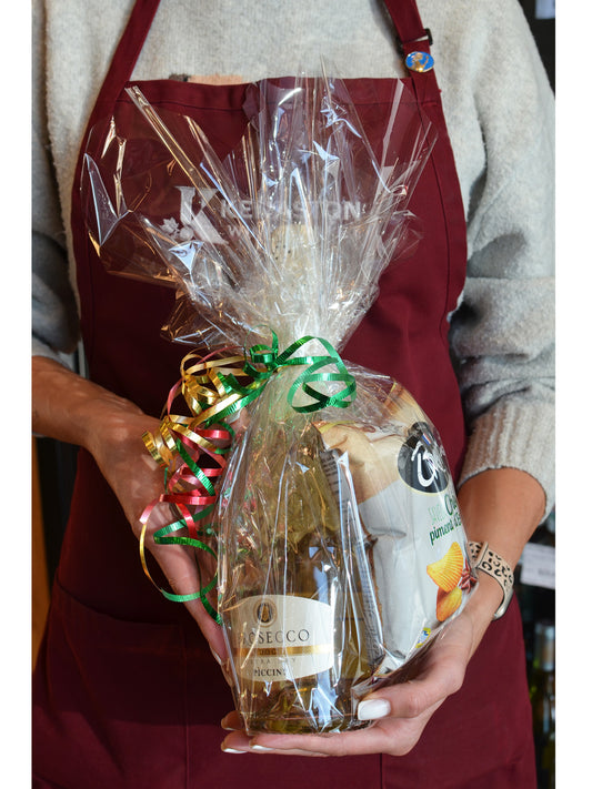 Person holding a cellophane-wrapped packet with a bottle of prosecco and a bag of potato crisps/chips tied up with colourful ribbons